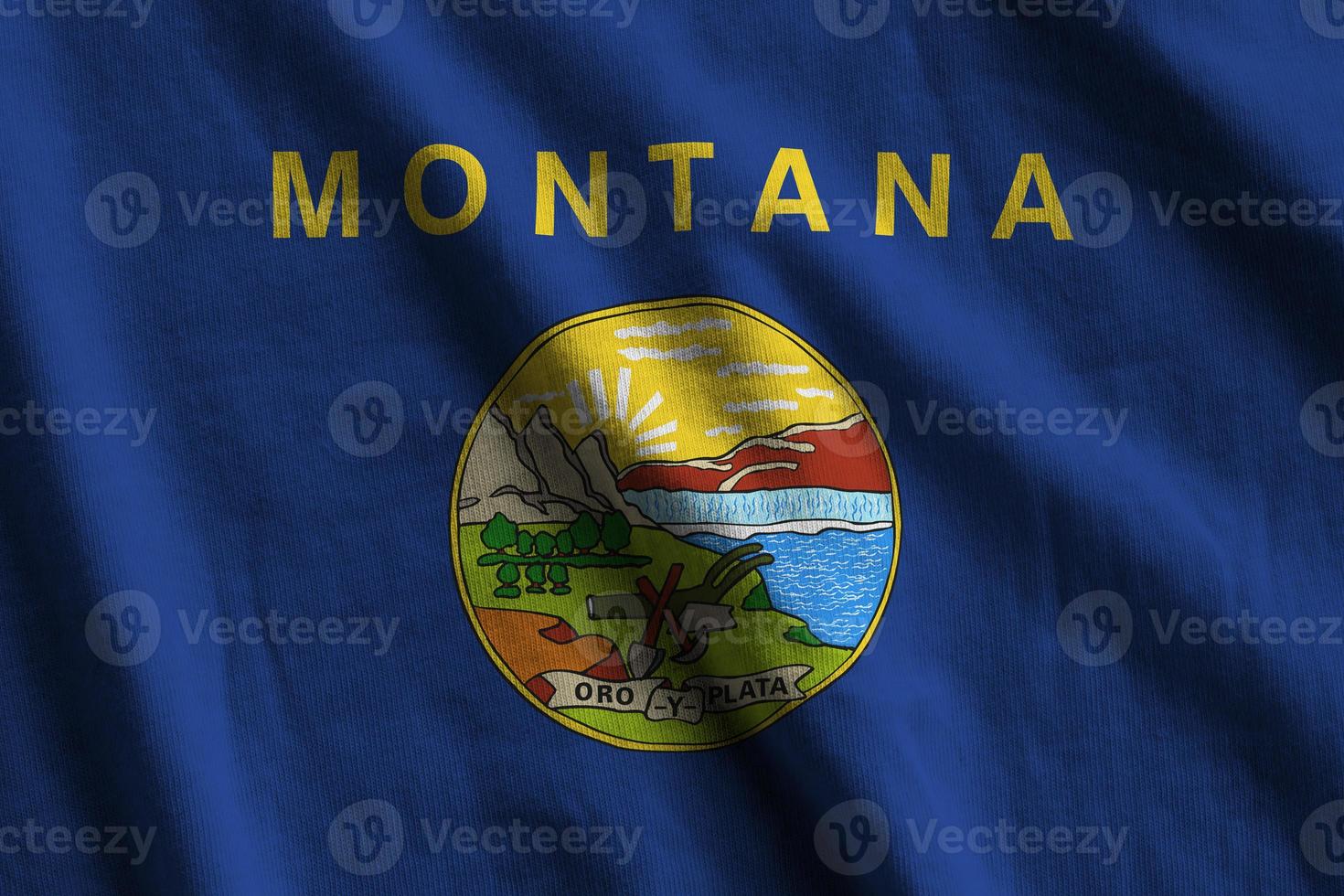 Montana US state flag with big folds waving close up under the studio light indoors. The official symbols and colors in banner photo