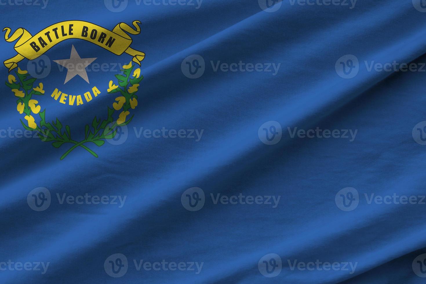 Nevada US state flag with big folds waving close up under the studio light indoors. The official symbols and colors in banner photo