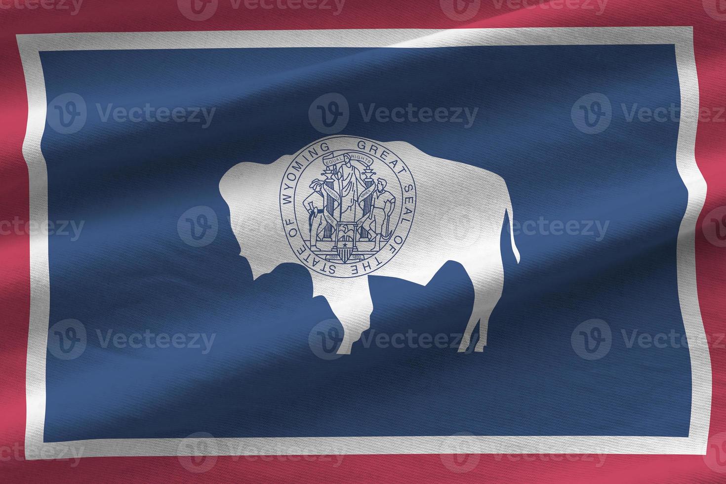 Wyoming US state flag with big folds waving close up under the studio light indoors. The official symbols and colors in banner photo