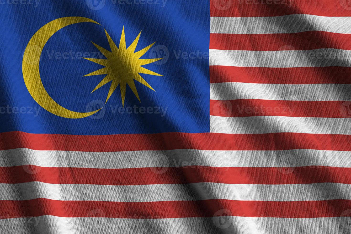 Malaysia flag with big folds waving close up under the studio light indoors. The official symbols and colors in banner photo