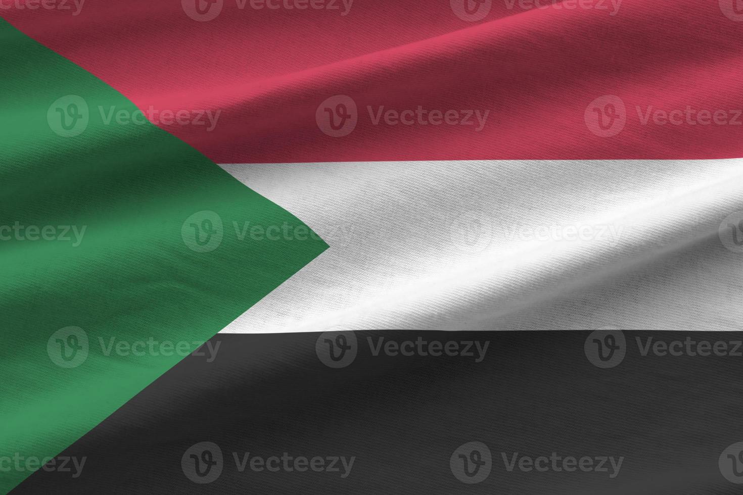 Sudan flag with big folds waving close up under the studio light indoors. The official symbols and colors in banner photo