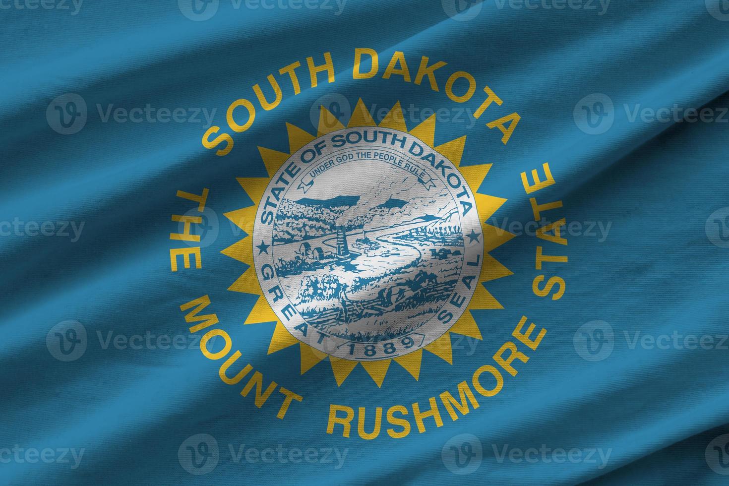 South Dakota US state flag with big folds waving close up under the studio light indoors. The official symbols and colors in banner photo