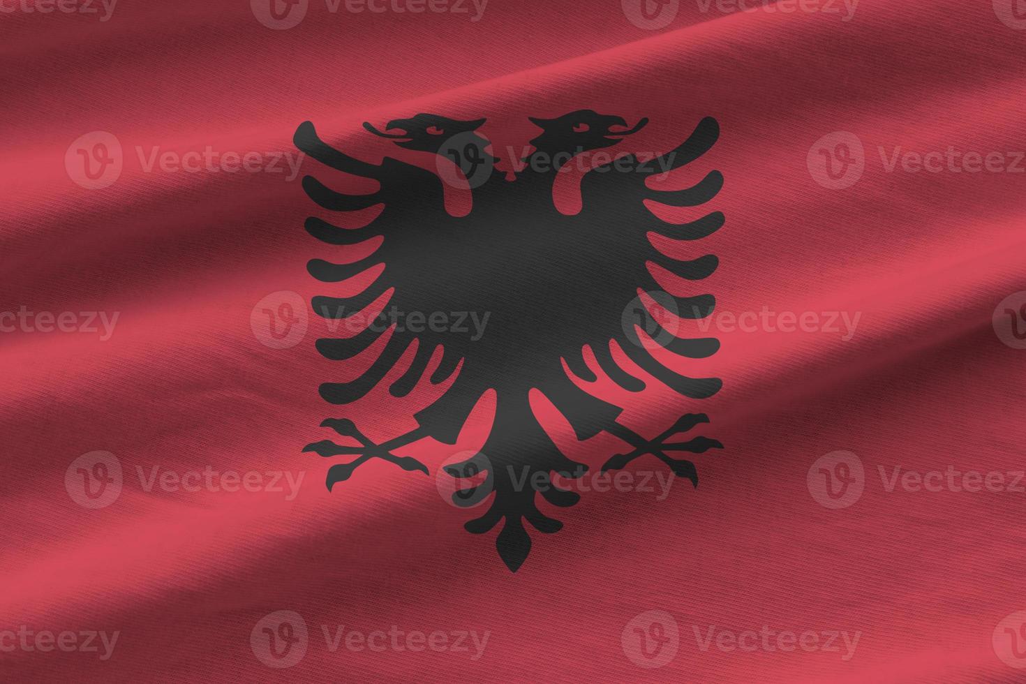 Albania flag with big folds waving close up under the studio light indoors. The official symbols and colors in banner photo