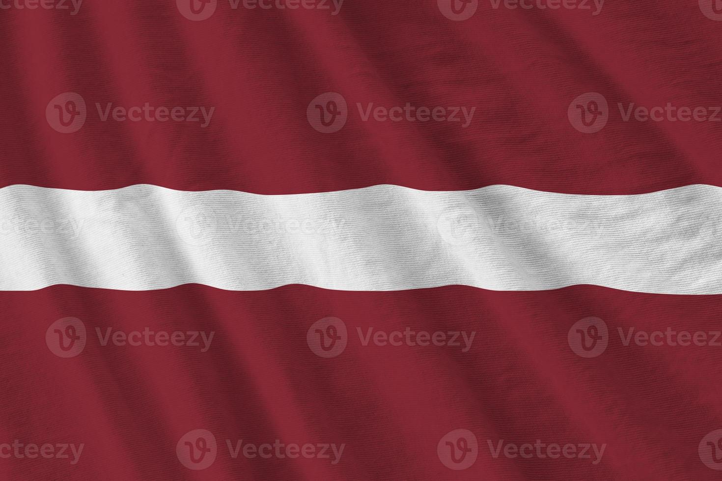 Latvia flag with big folds waving close up under the studio light indoors. The official symbols and colors in banner photo