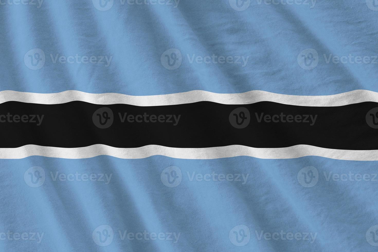 Botswana flag with big folds waving close up under the studio light indoors. The official symbols and colors in banner photo
