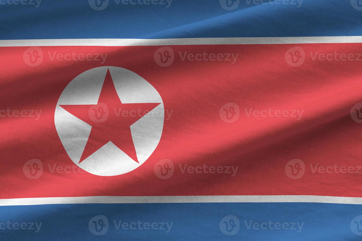 North Korea flag with big folds waving close up under the studio light indoors. The official symbols and colors in banner photo