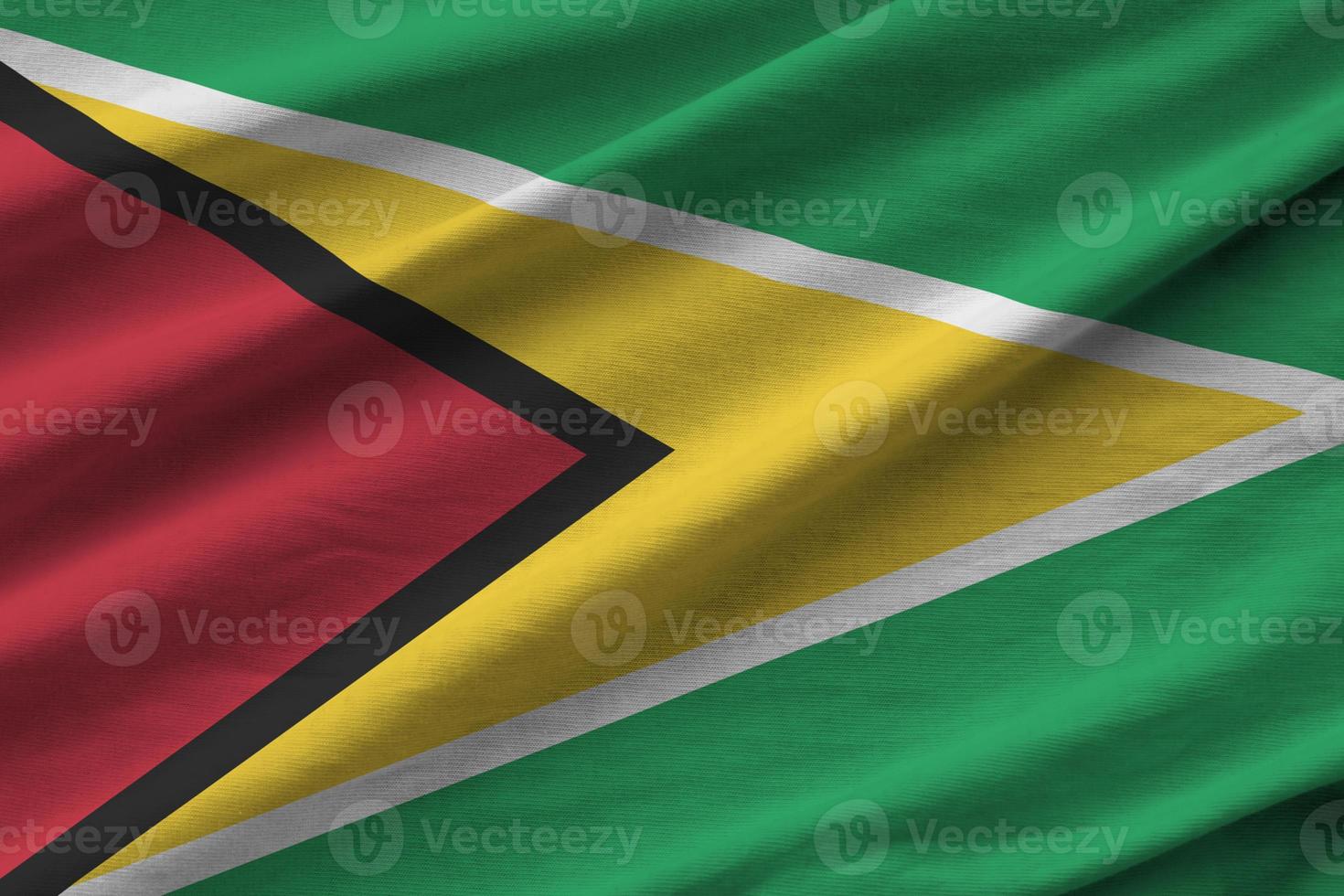 Guyana flag with big folds waving close up under the studio light indoors. The official symbols and colors in banner photo