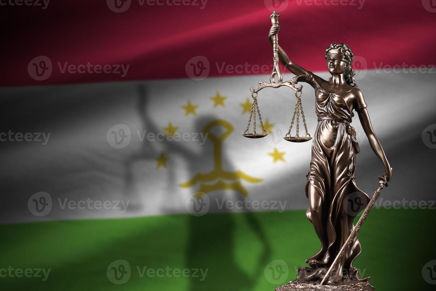 Tajikistan flag with statue of lady justice and judicial scales in dark room. Concept of judgement and punishment photo