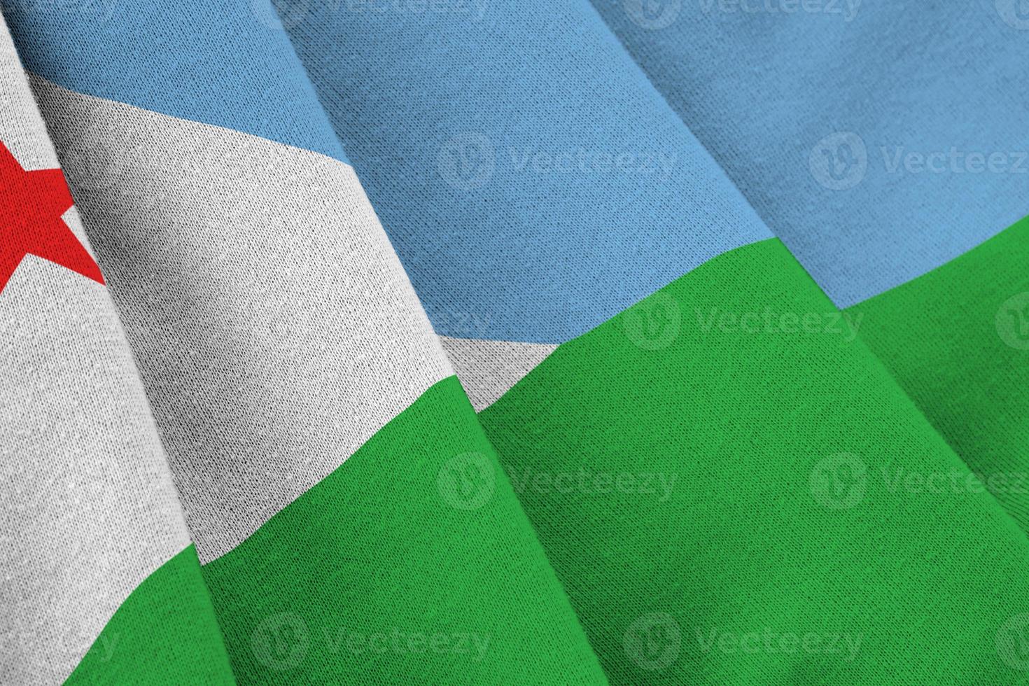 Djibouti flag with big folds waving close up under the studio light indoors. The official symbols and colors in banner photo