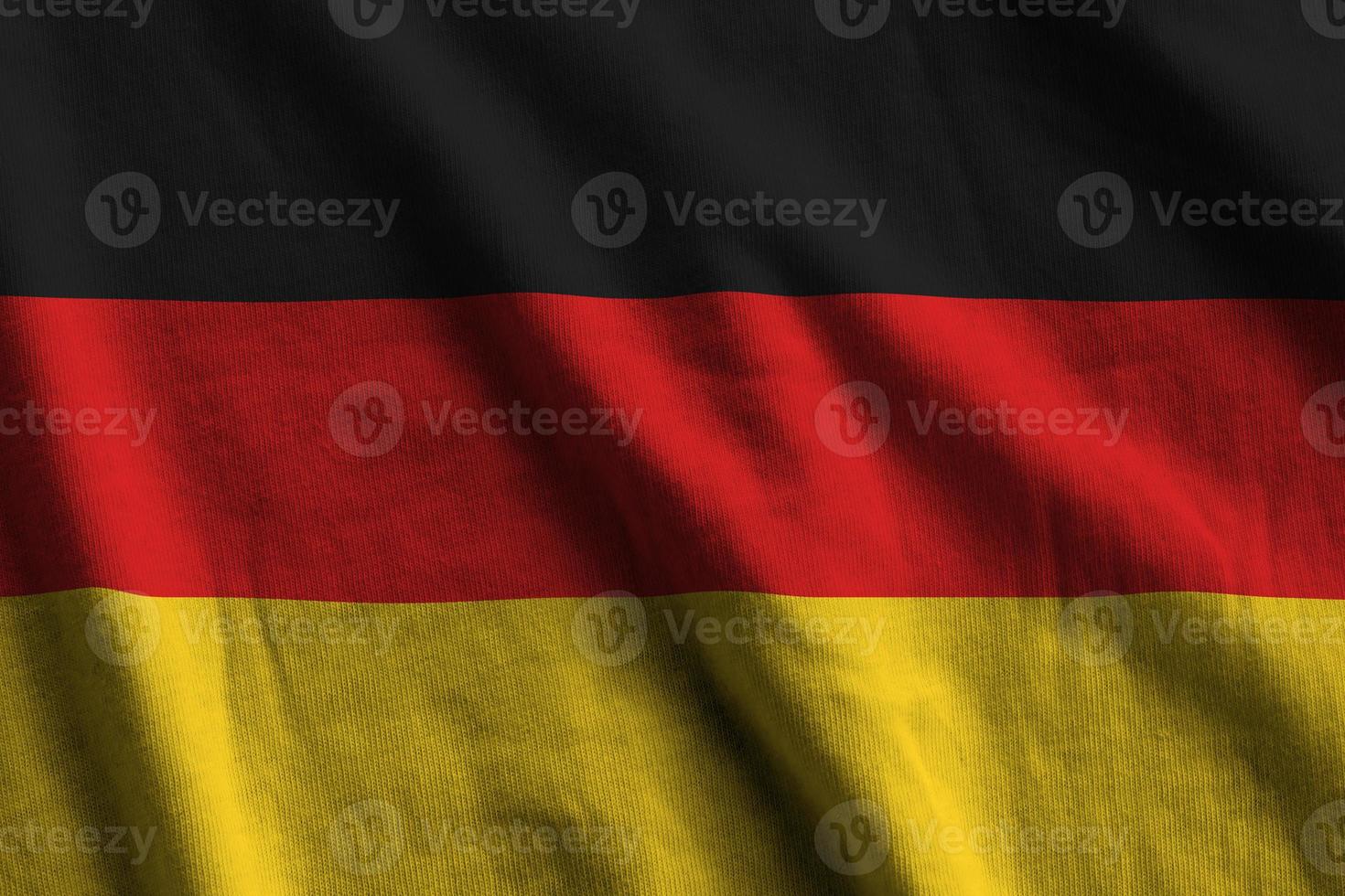 Germany flag with big folds waving close up under the studio light indoors. The official symbols and colors in banner photo