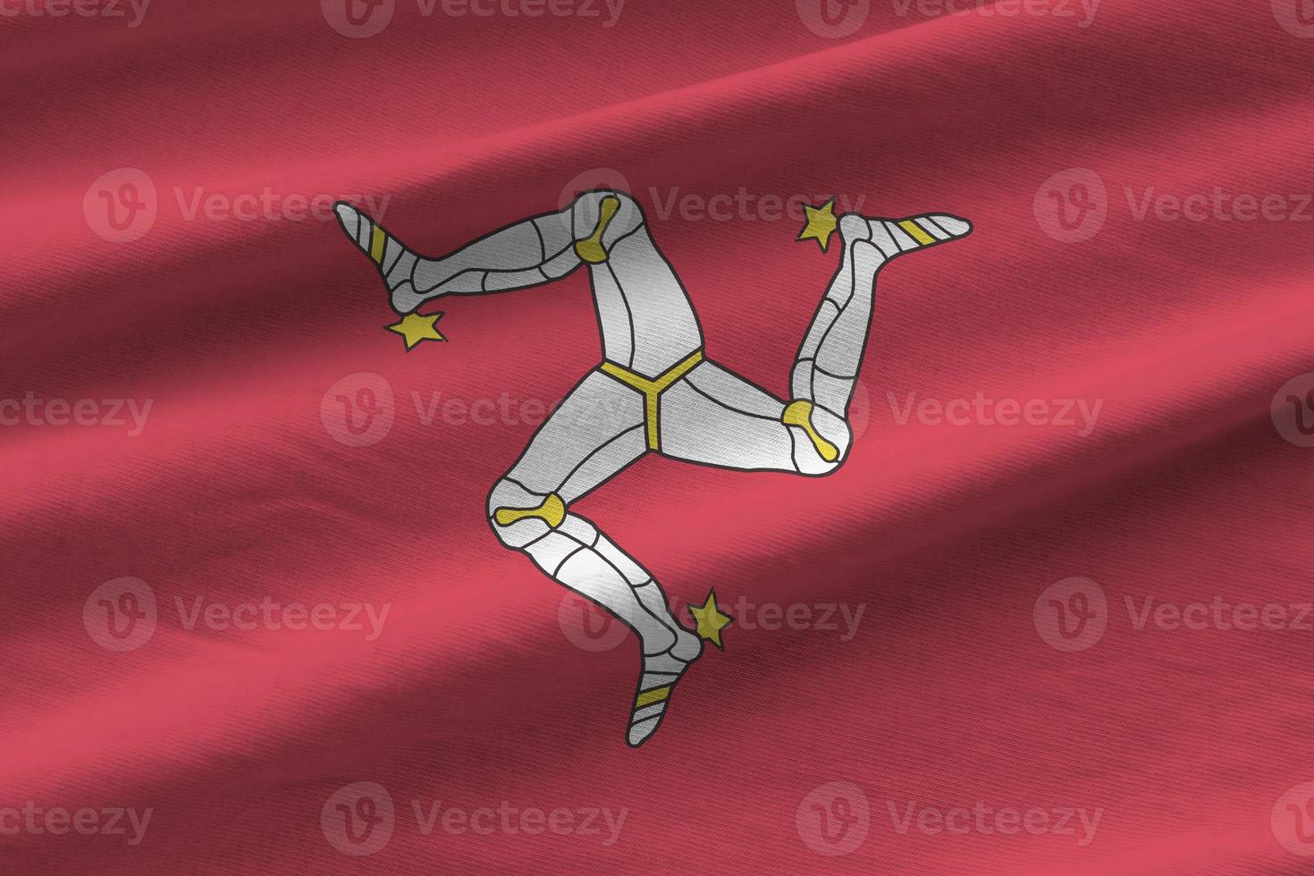 Isle of Man flag with big folds waving close up under the studio light indoors. The official symbols and colors in banner photo