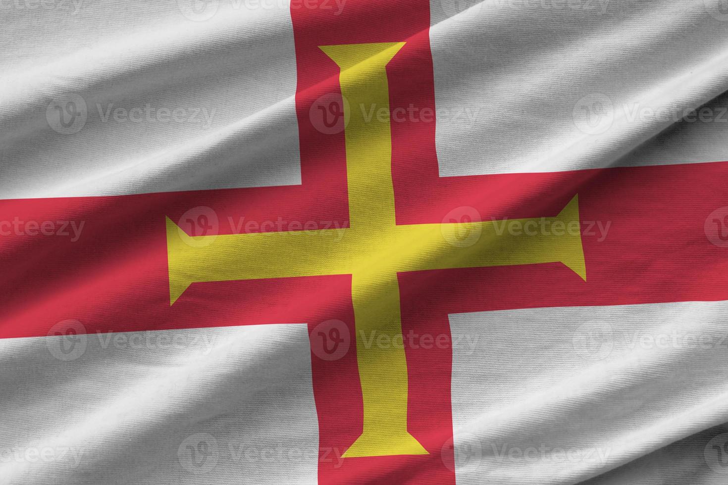 Guernsey flag with big folds waving close up under the studio light indoors. The official symbols and colors in banner photo