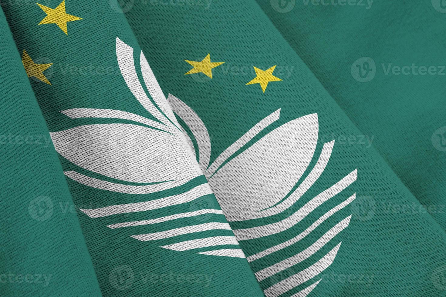 Macau flag with big folds waving close up under the studio light indoors. The official symbols and colors in banner photo