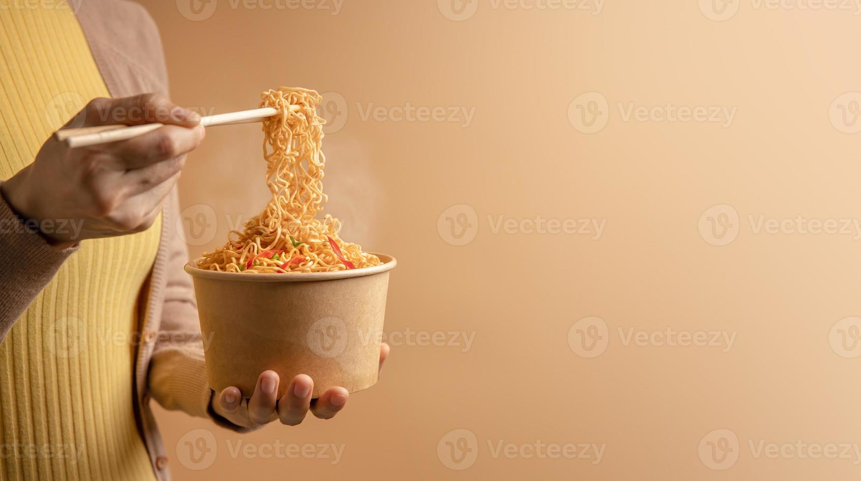 Woman Using Chopsticks to Eating Hot Boiled Instant Cup Noodles. Cheap Asian Fast food Concepts. Side View photo