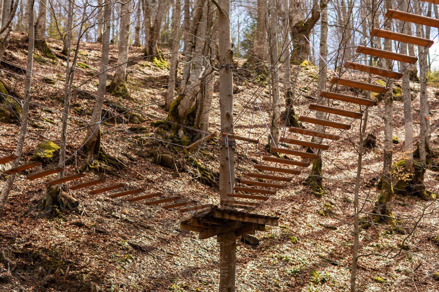 Rope park in the middle of the forest.Passing sports obstacles above the ground.Outdoor activities.Sports park for the whole family.Hanging steps and ropes strung between trees.Wooden Town photo