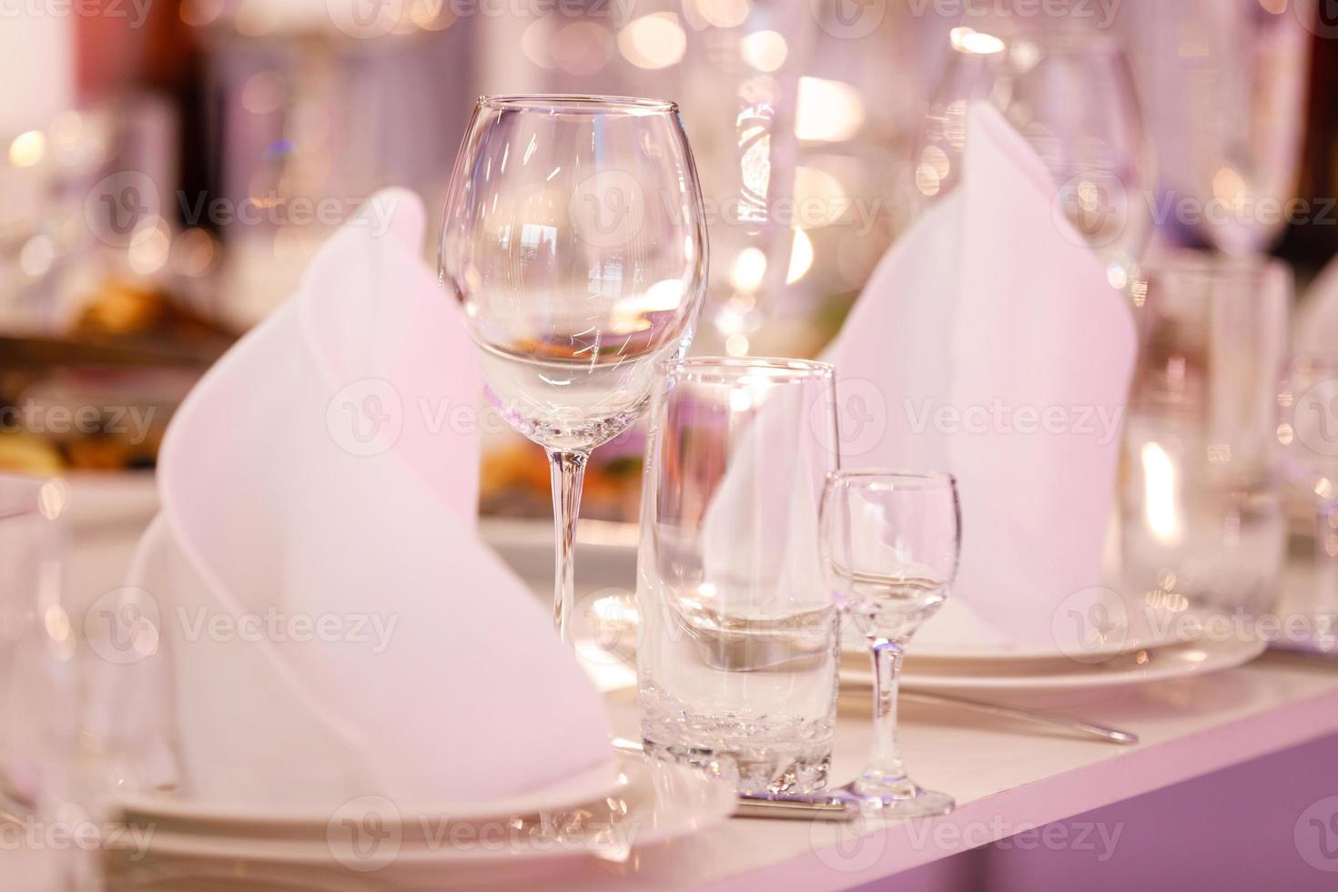 Empty glass set in restaurant. wedding, decor, celebration, holiday concept - romantic table setting with white tablecloth, plates, crystal glasses photo