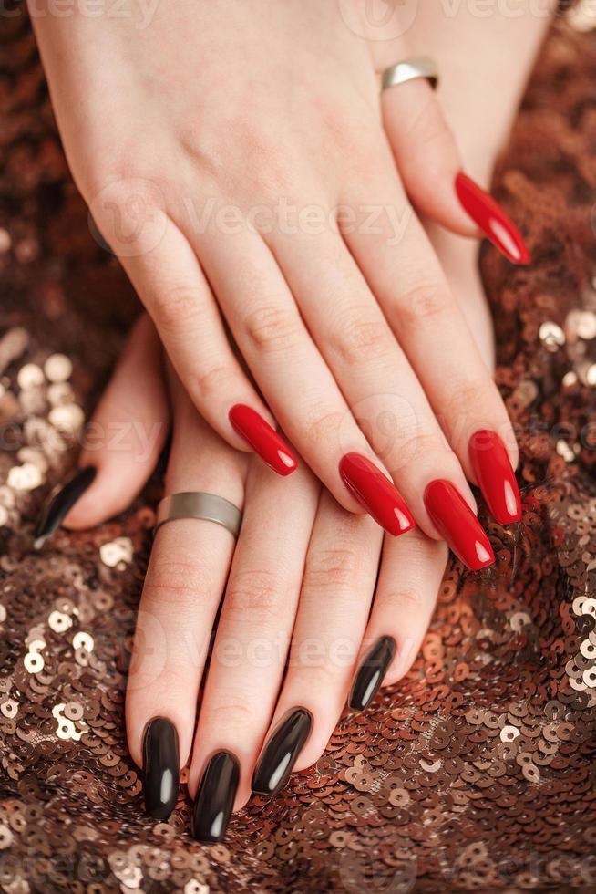 Hands of a young girl with red  and black manicure on nails photo