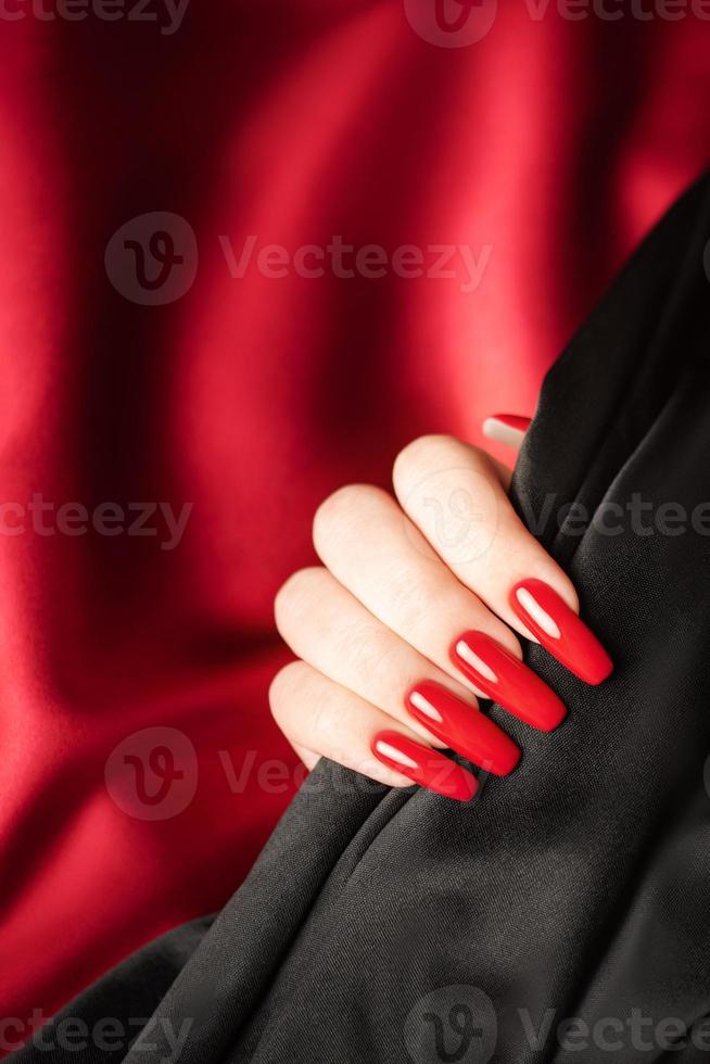 manos de una joven con manicura roja y negra en las uñas foto