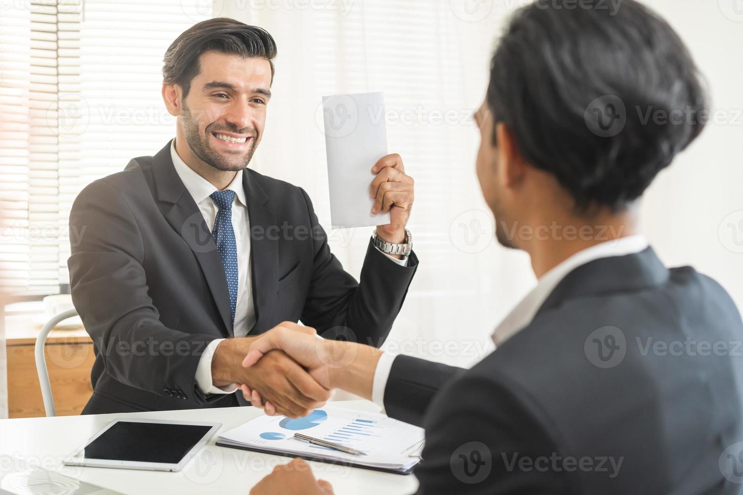 Handshake, caucasian male giving financial reward in an envelope, business letter extra salary to company employee, asian manager man worker office hand received premium bonus,getting cheque from boss photo