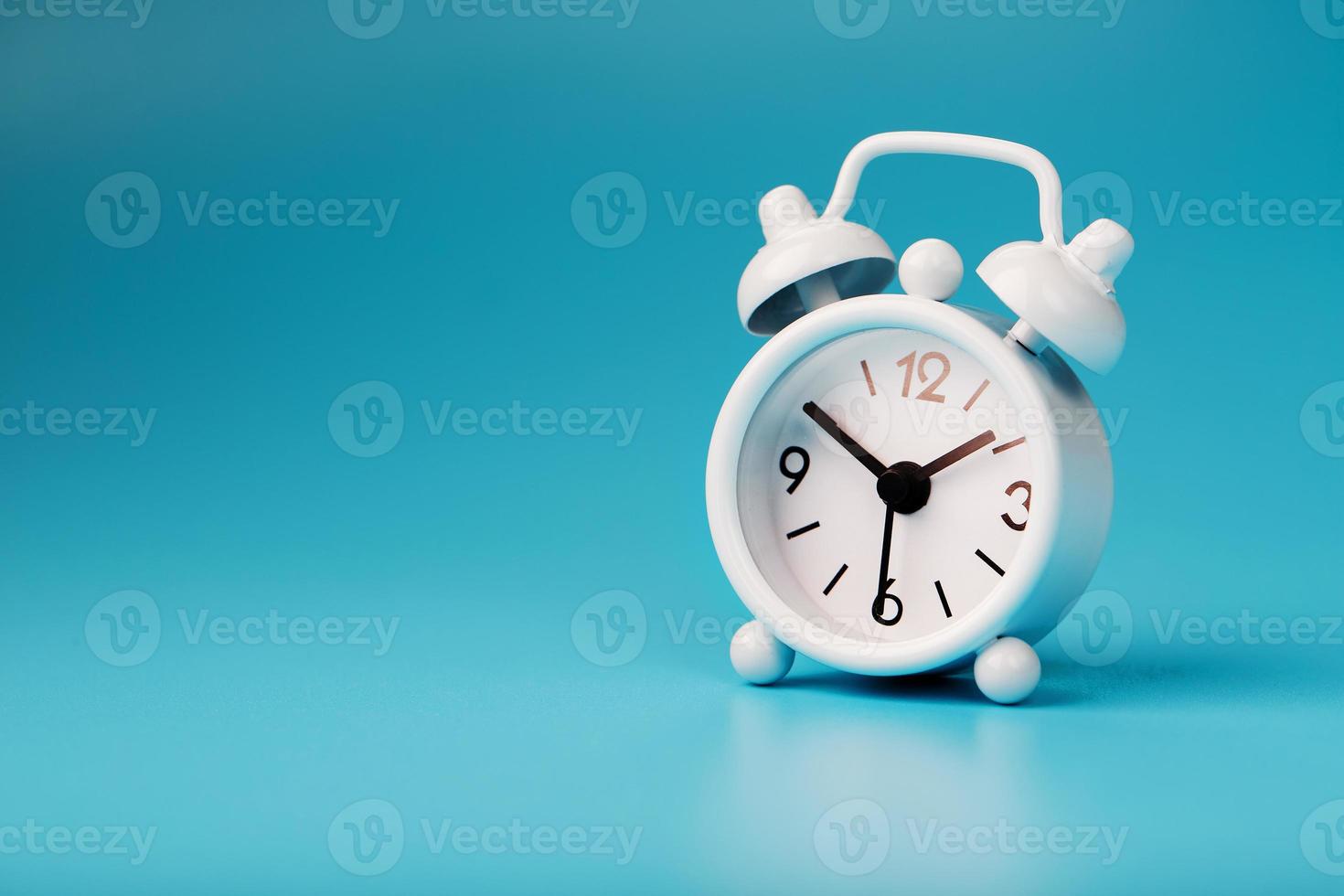 White retro alarm clock on blue background. Concept of time with free space for text. photo