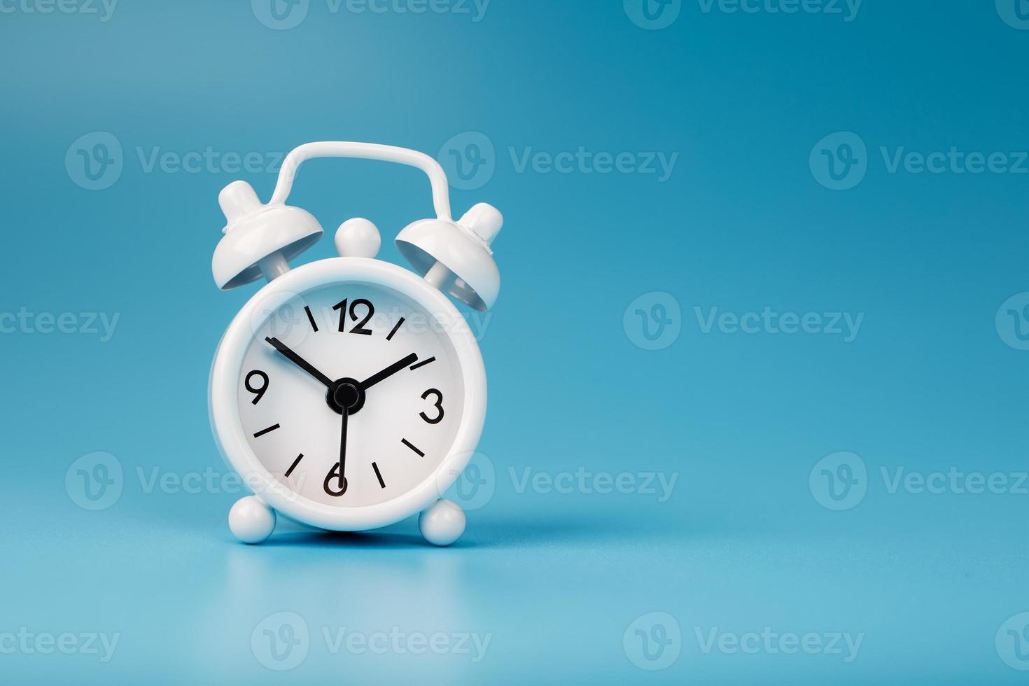 blanco retro alarma reloj en azul antecedentes. concepto de hora con gratis espacio para texto. foto