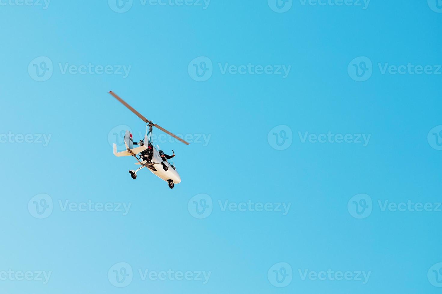 White small double gyroplane autogyro without a cabin against the blue sky. Air tours for tourists. photo