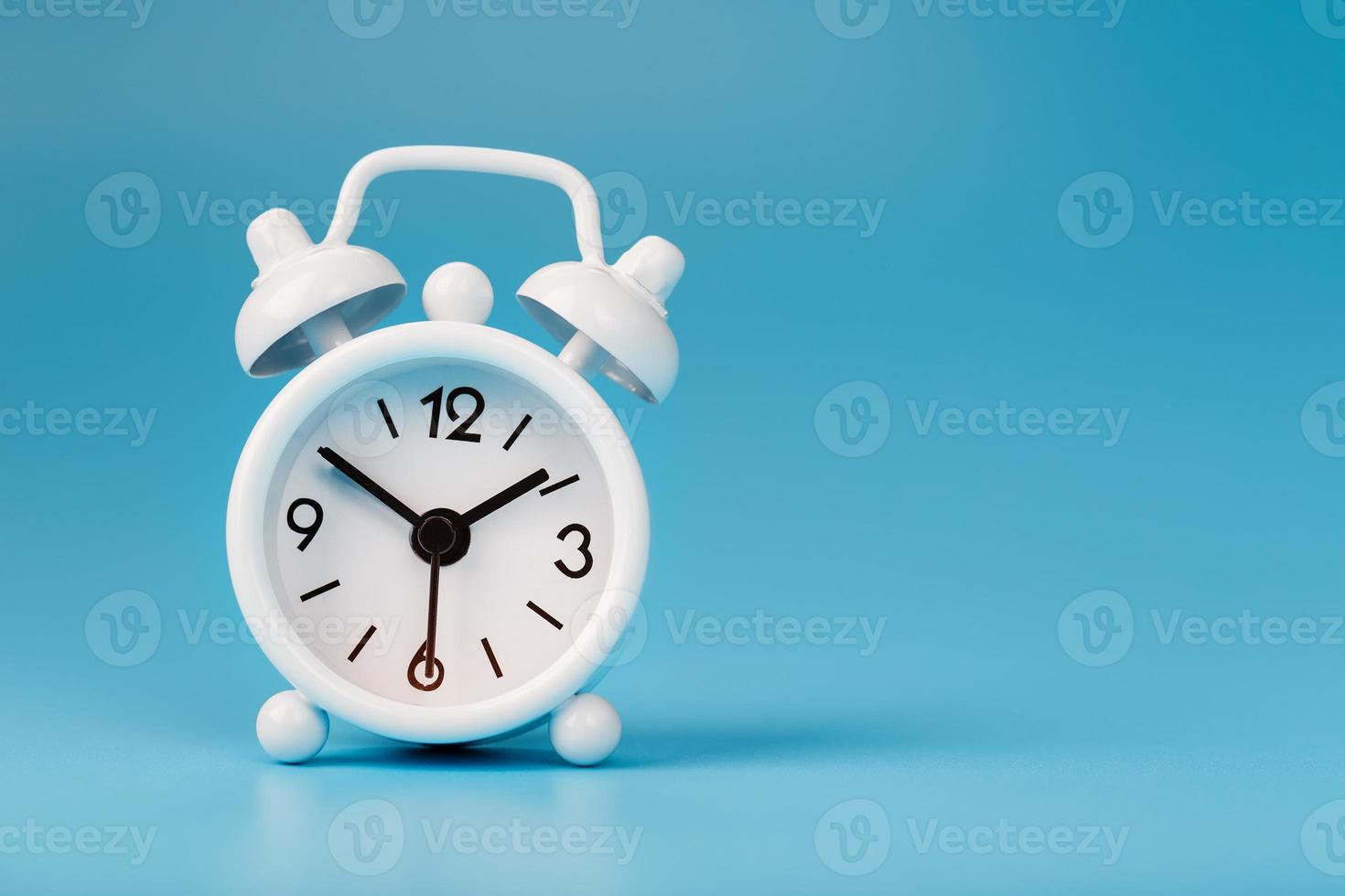 White retro alarm clock on blue background. Concept of time with free space for text. photo