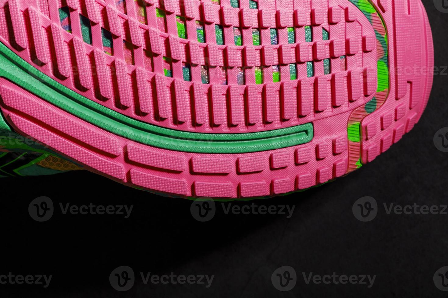 Textured pink sole of sports running shoes on a black background. photo