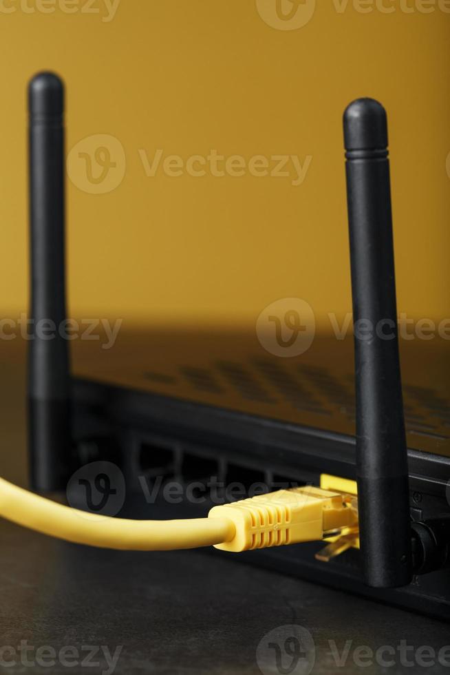 A yellow patch cord is inserted into the Wi-Fi port of the router to access the Internet. photo