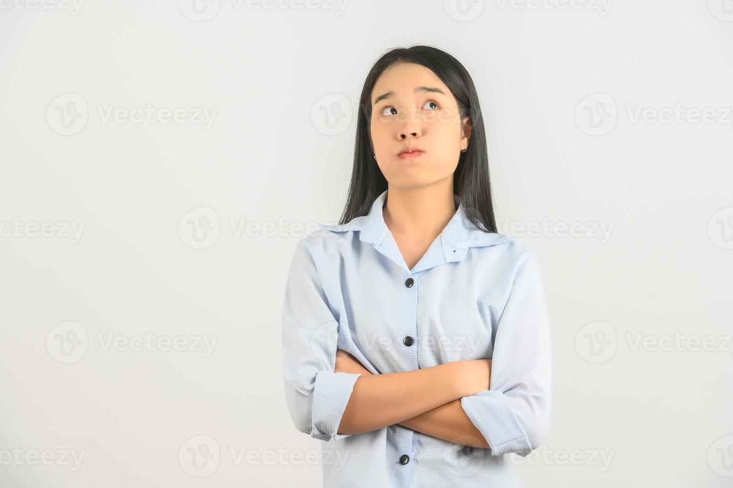 retrato de joven asiático mujer en azul camisa pensando y cruzado brazo aislado en blanco antecedentes foto