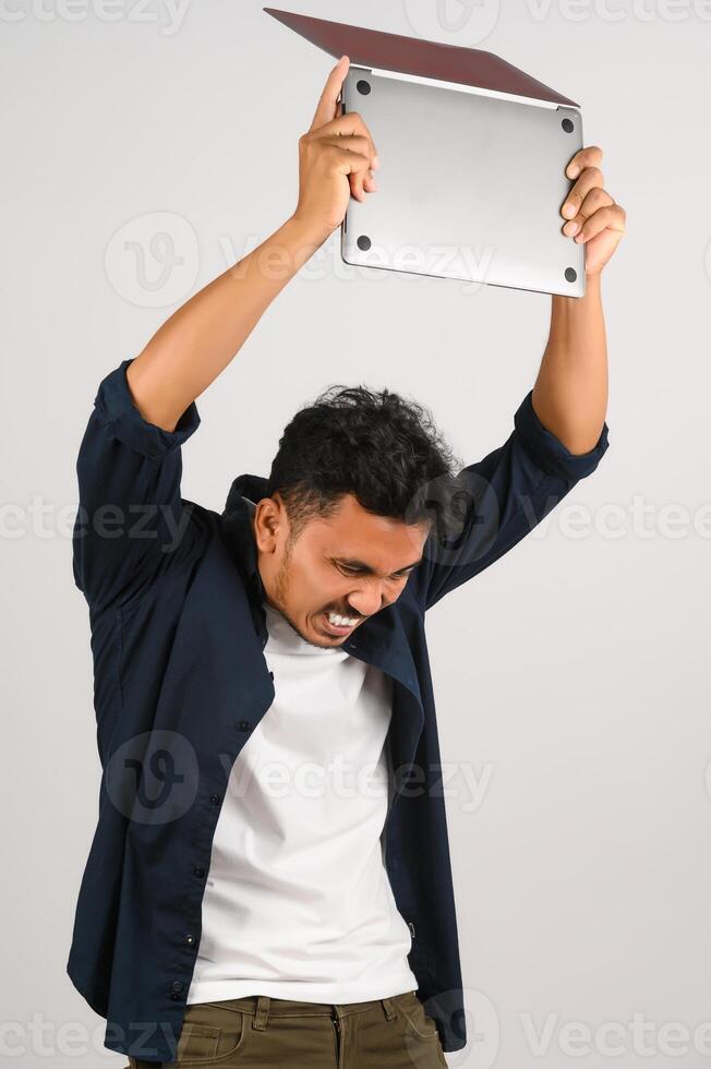 Portrait of anger asian businessman working on laptop computer isolated over white background photo