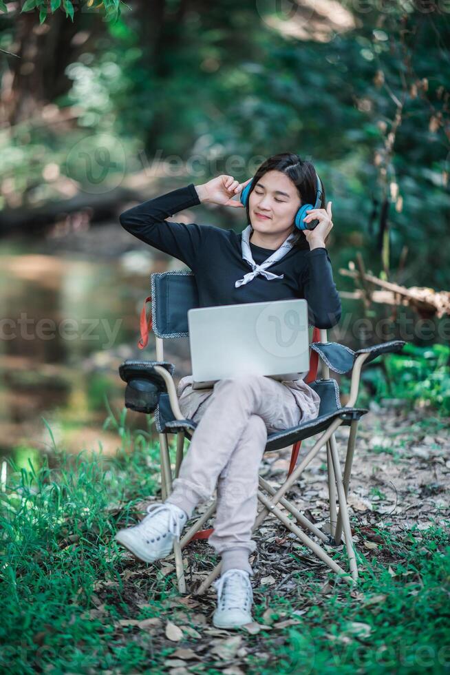 Young woman wearing headphone listening music from laptop photo