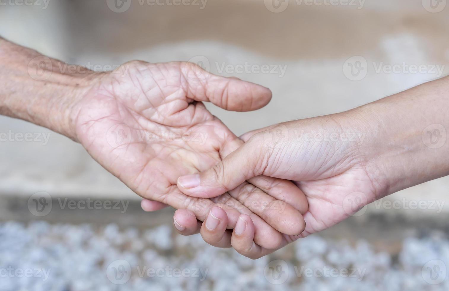 Close-up of old and young holding hands. Middle-aged mommy's wrinkled hands holding young daughters, a millennial woman supporting mature mum, showing care, and love. Support for the elderly concept. photo