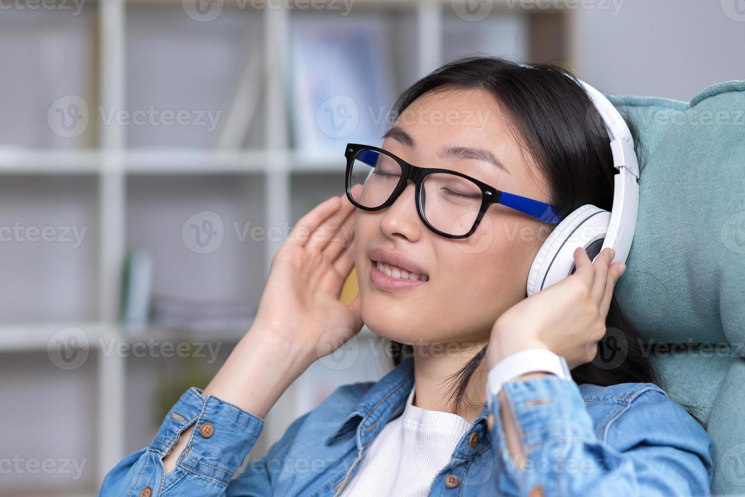 de cerca retrato de un joven asiático mujer con cerrado ojos, escuchando a música foto