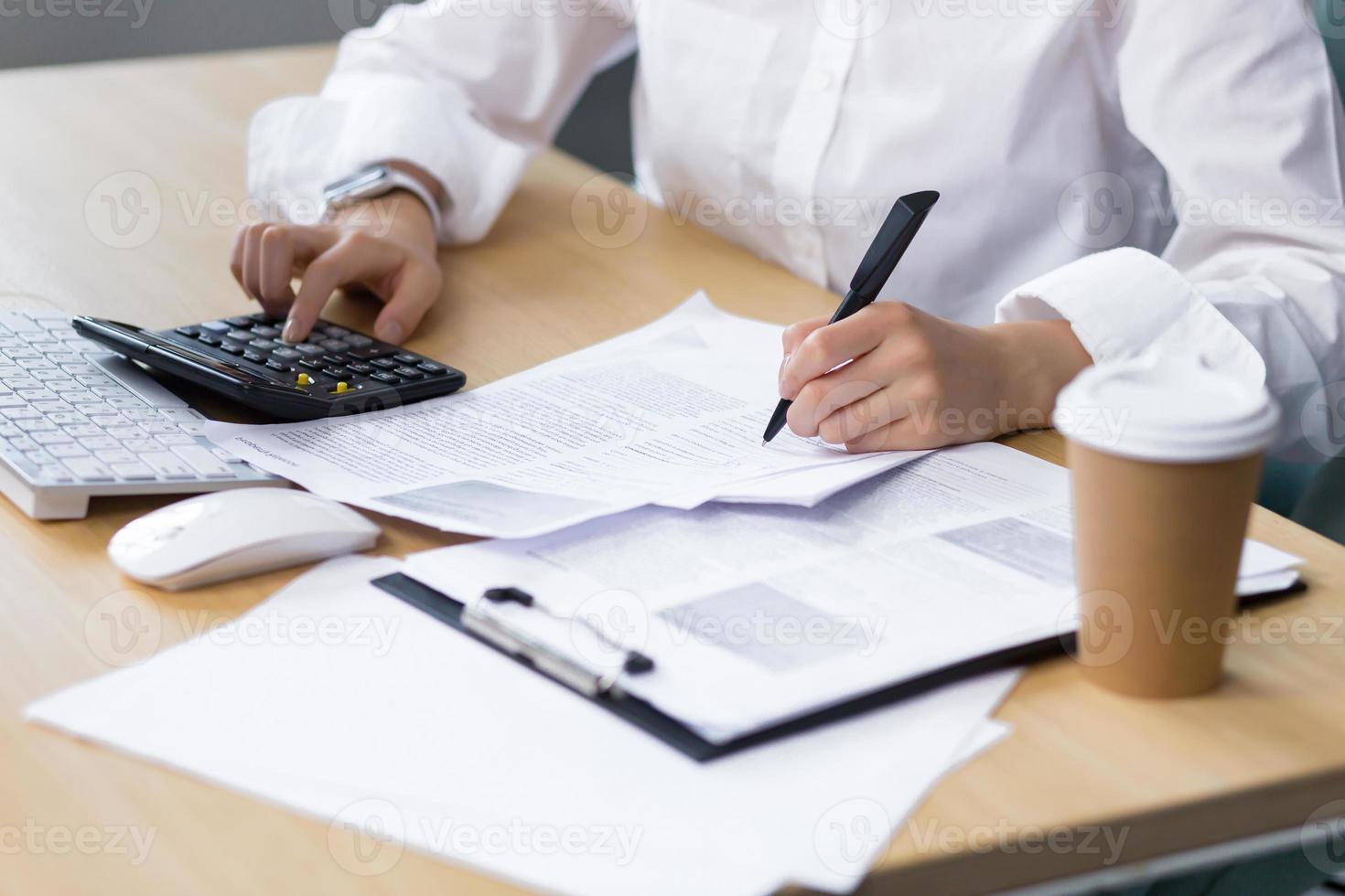 Close-up photo of a business woman's hand on paper work, an accountant calculates