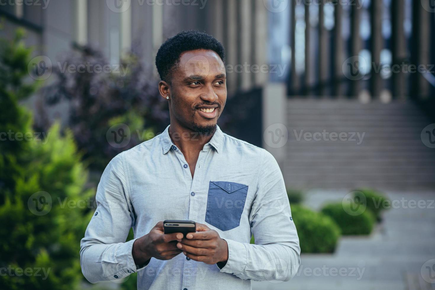 Young happy african american male freelancer corresponding in mobile and reading good news photo