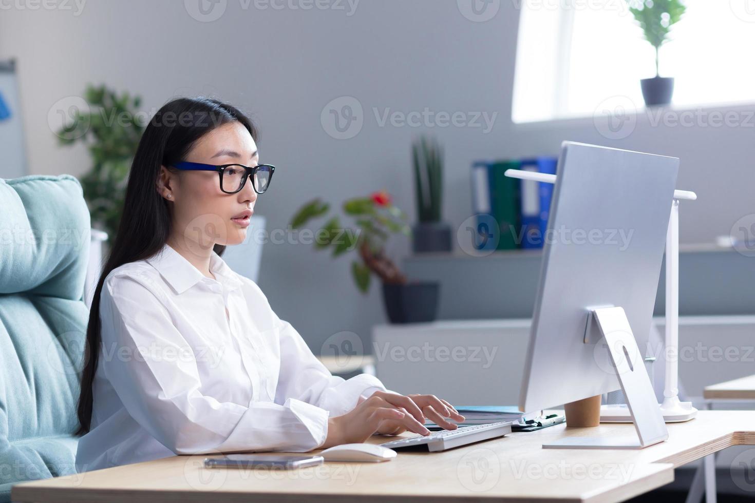 un joven hermosa asiático mujer es trabajando a un computadora en el oficina. mujer de negocios, director foto
