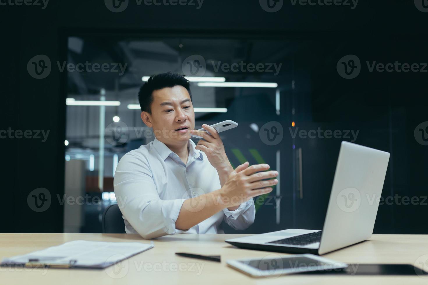 Online store. A young Asian salesman talks on the phone with customers, offers them to buy goods. photo