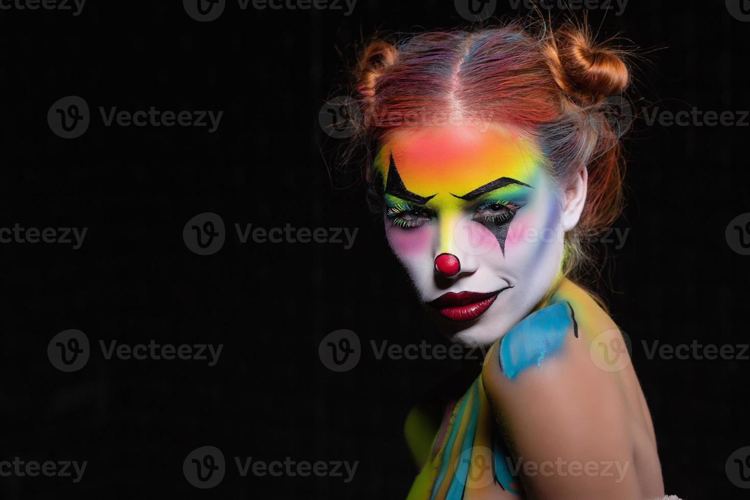 Charming young woman with a face painting clow photo