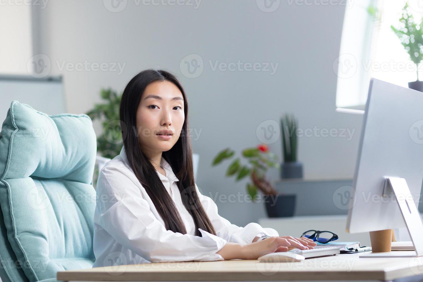 Close-up photo. Portrait of a young Asian woman secretary sitting at the computer in the office photo
