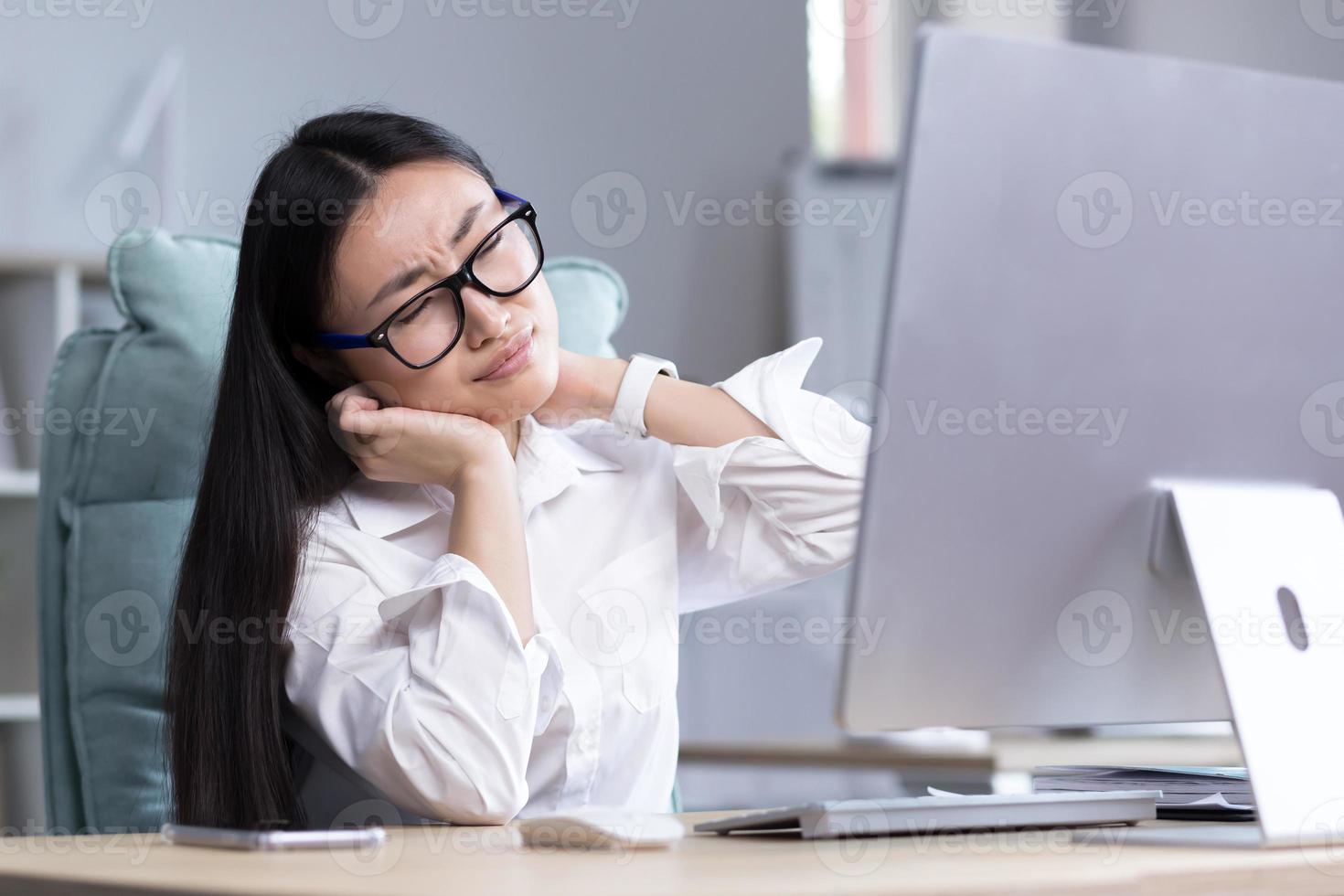 Overtired Asian woman office worker, has severe neck pain photo