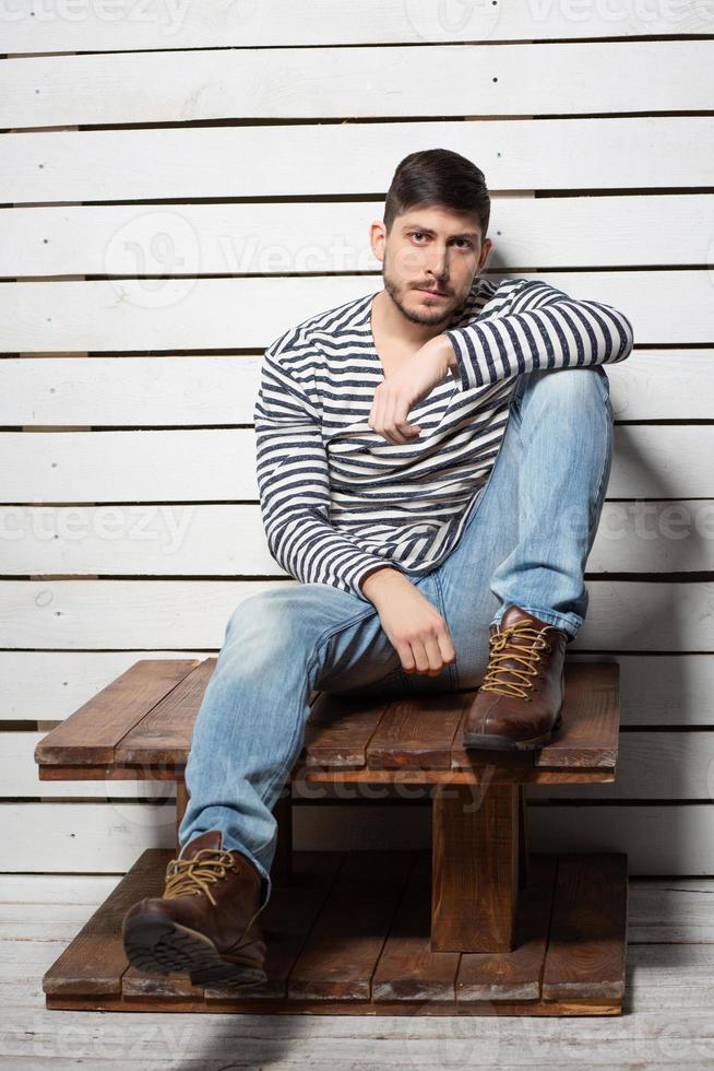 A young man sits on a wooden table photo