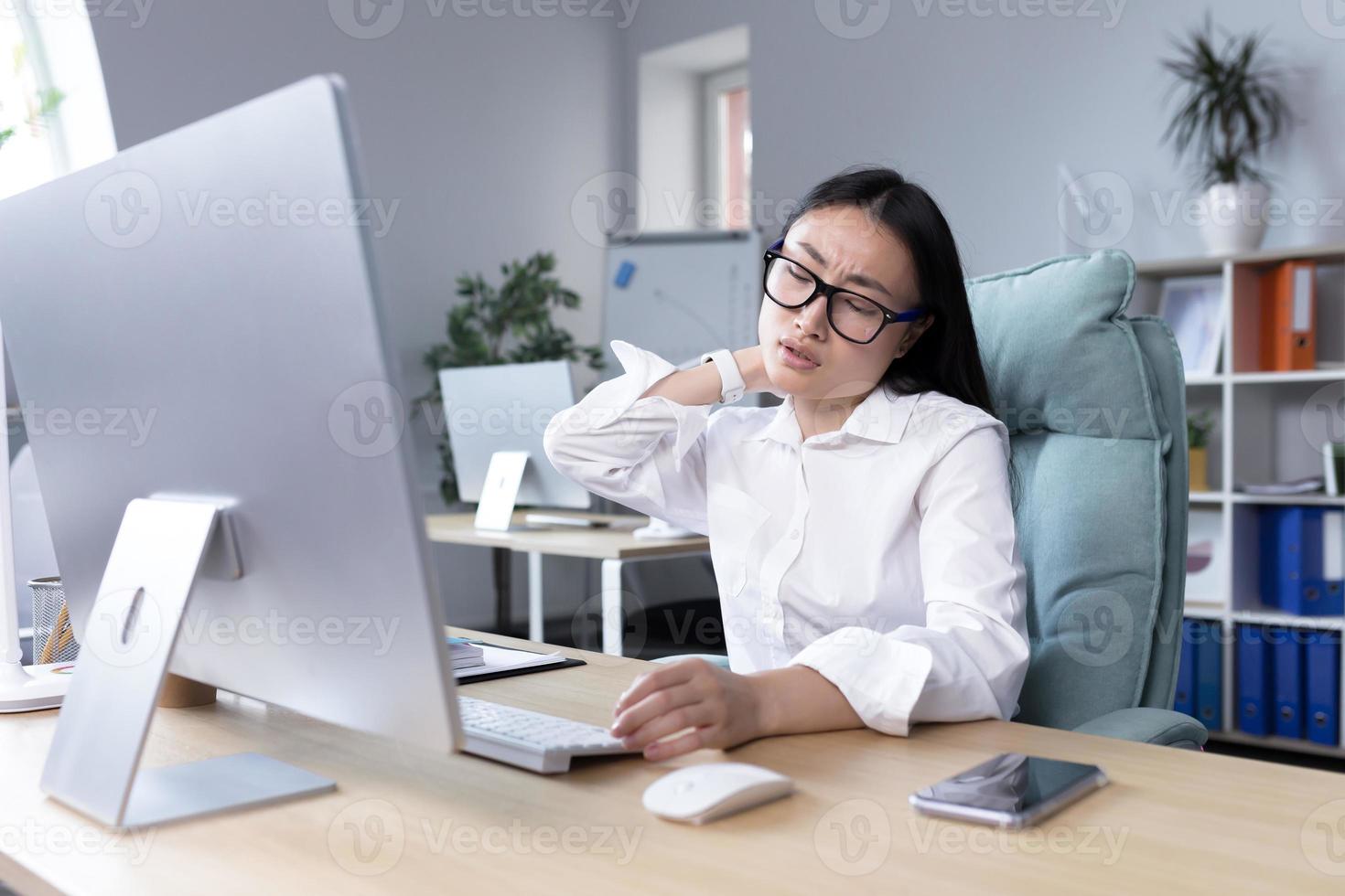 Overtired Asian woman office worker, has severe neck pain photo