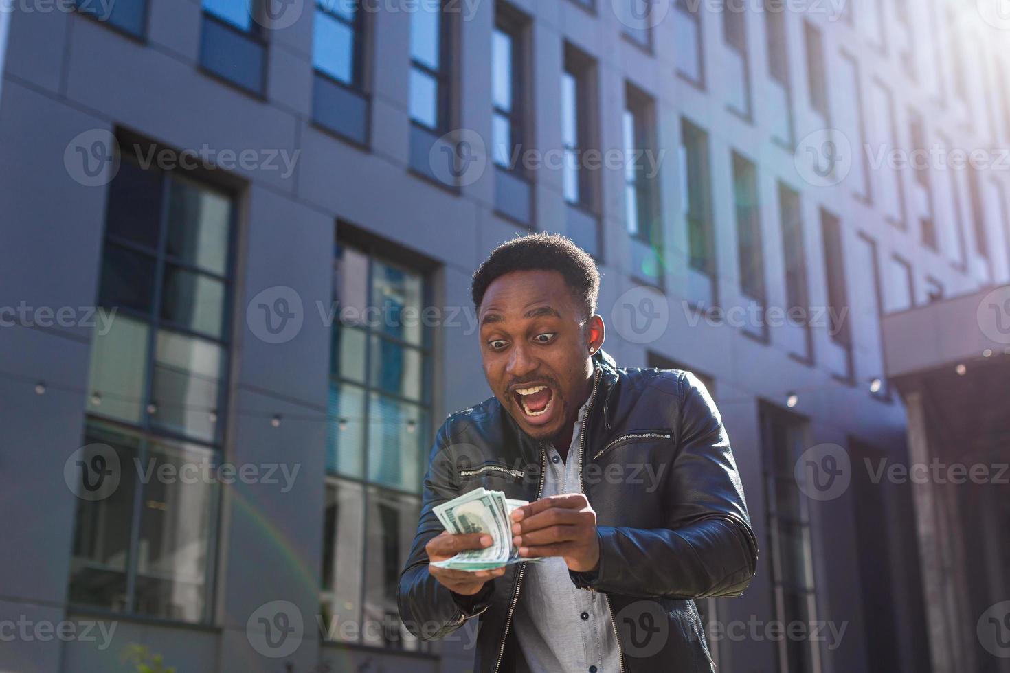 Happy successful African American guy counts, waves, throws, show off, flaunt, cash money photo