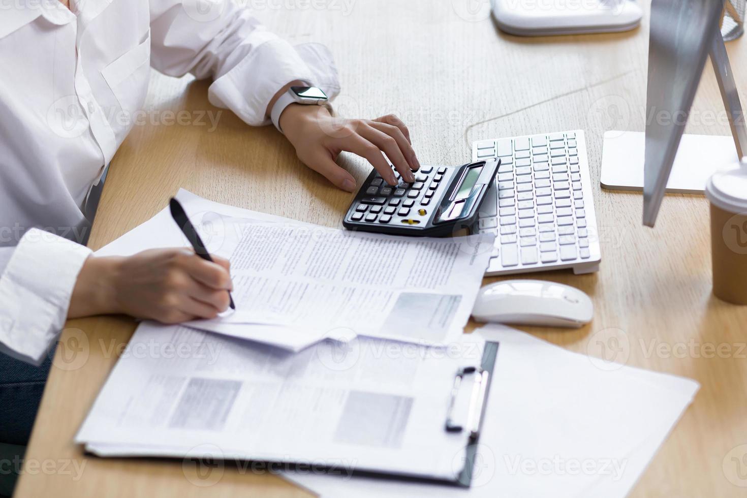 Close-up photo of a business woman's hand on paper work, an accountant calculates