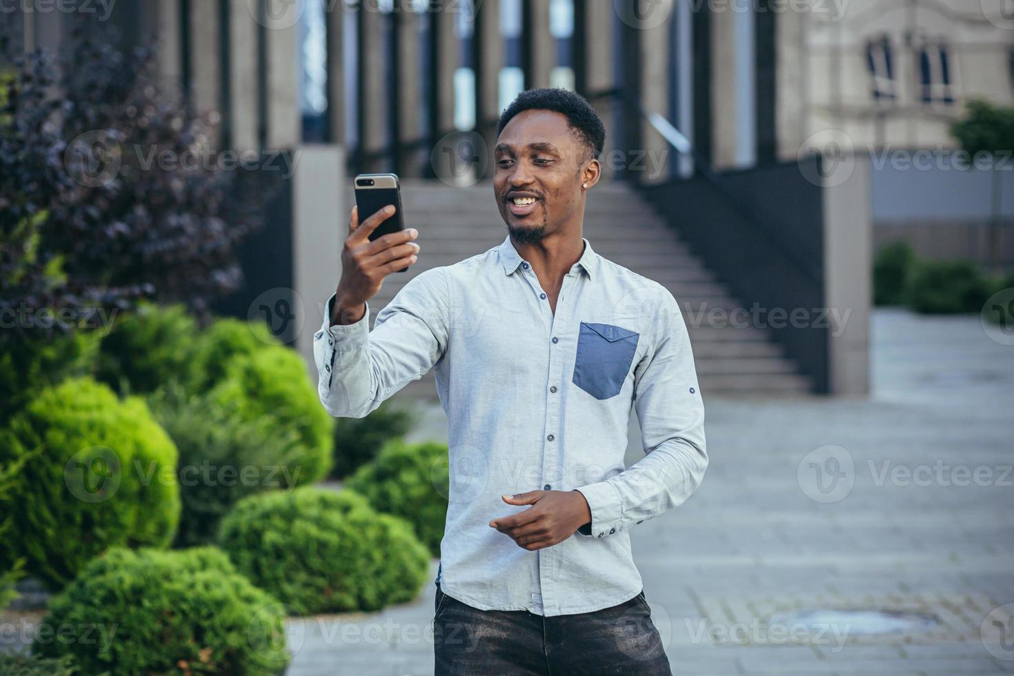 Young african american freelancer talking on video call near office cheerful smiling man photo