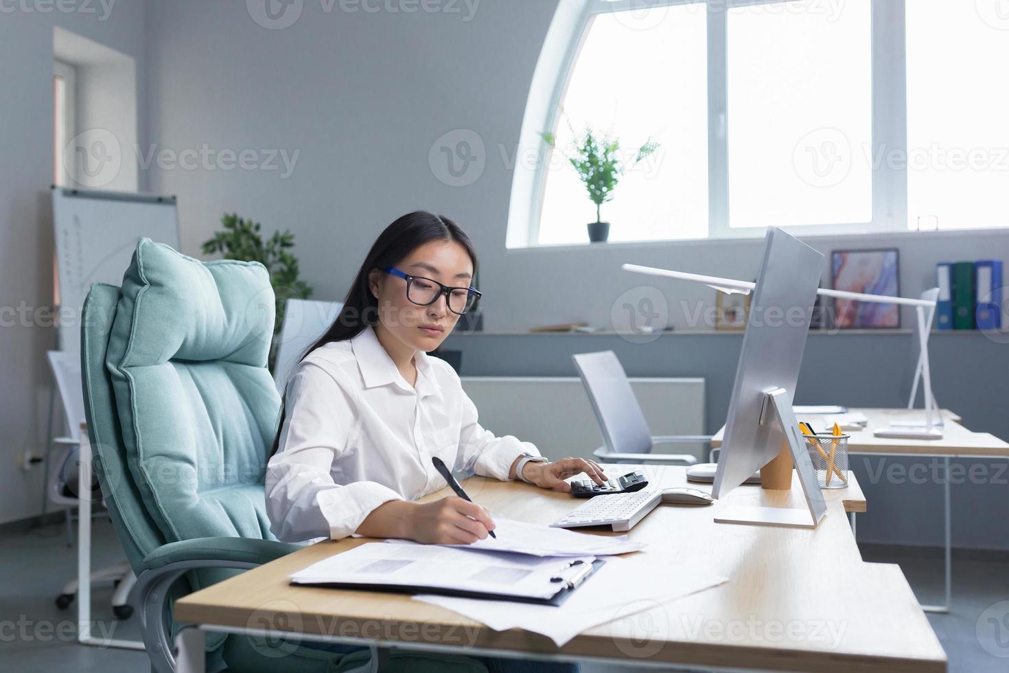 retrato de un joven negocio mujer asiático contador trabajos con documentos y informes foto