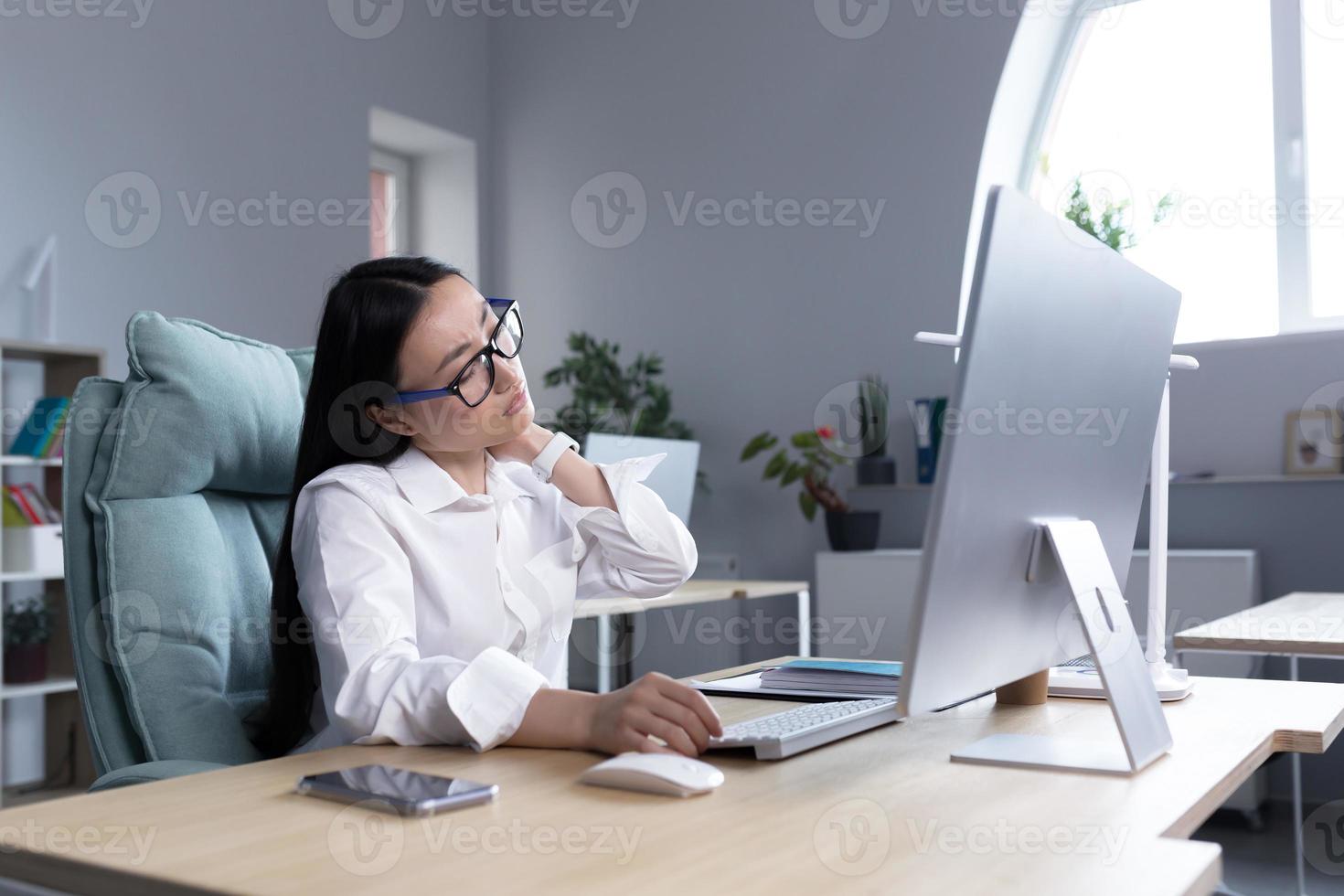 Overtired Asian woman office worker, has severe neck pain photo