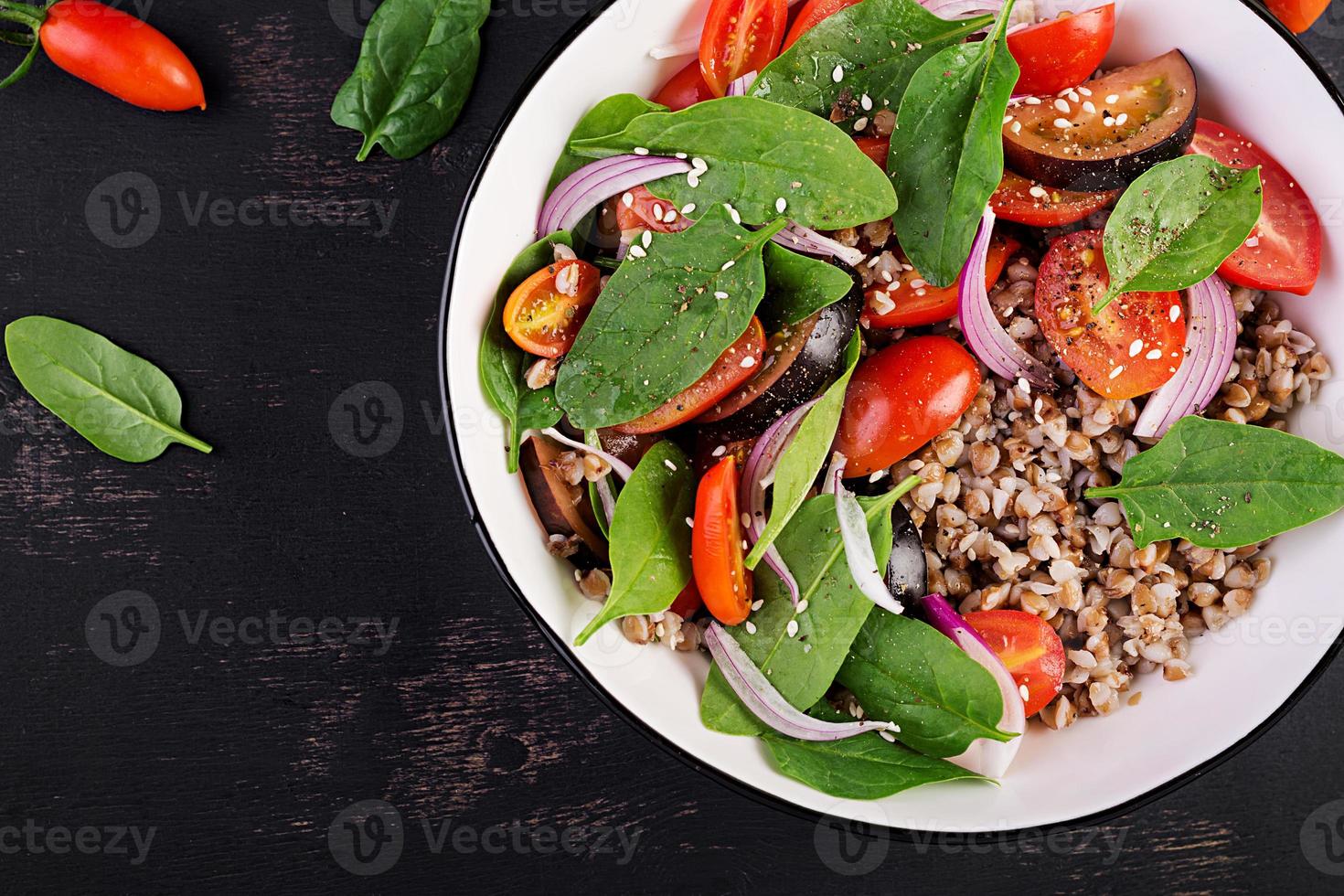 alforfón ensalada con Cereza Tomates, rojo cebolla y Fresco Espinacas. vegano alimento. dieta menú. parte superior vista. plano laico foto