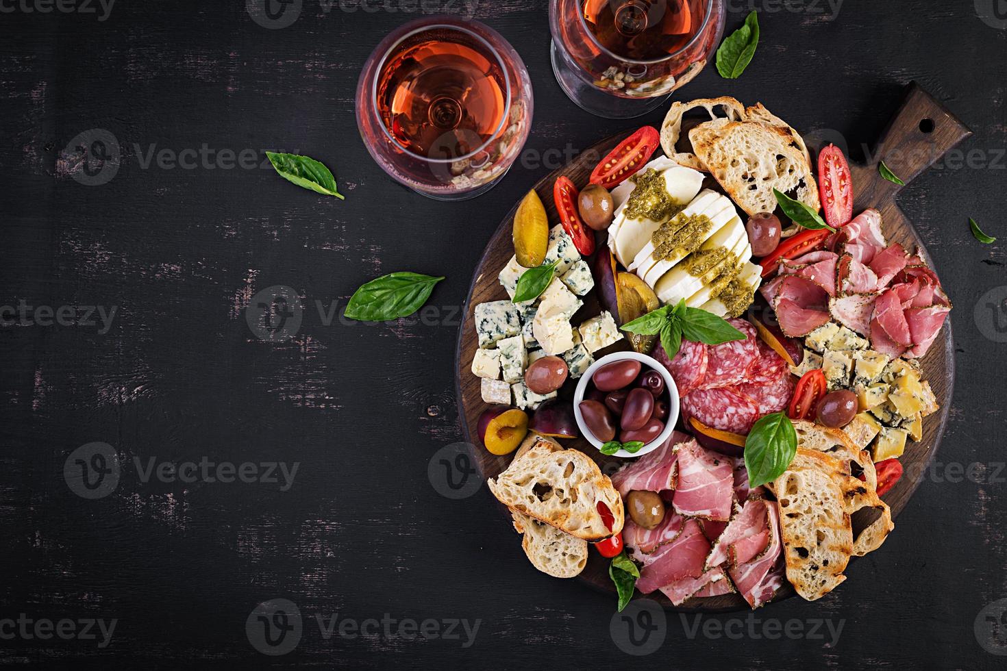 Antipasto platter with ham, prosciutto, salami, blue cheese, mozzarella with pesto and olives on a wooden background. Top view, overhead photo